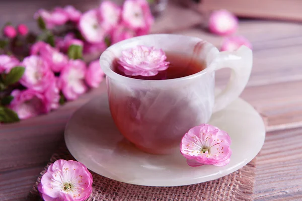 Bellissimo fiore di frutta con tazza di tè sul tavolo su sfondo grigio — Foto Stock