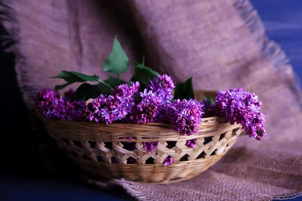 Lindas flores lilás na cesta de vime, na cor de fundo de madeira — Fotografia de Stock