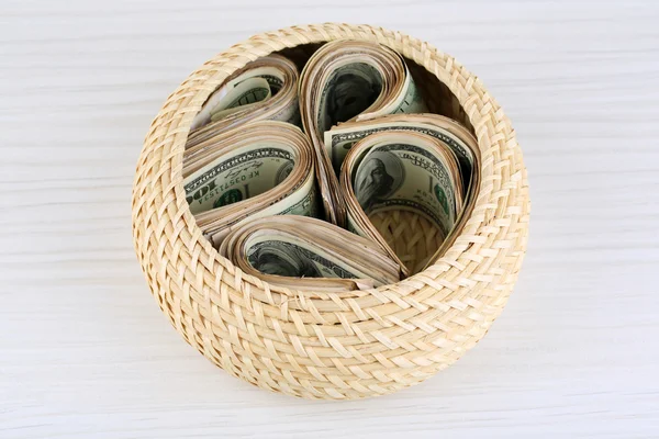 Packs of dollars stored in basket on wooden table — Stock Photo, Image