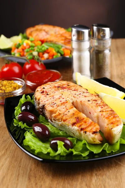 Schmackhafter gegrillter Lachs mit Zitrone und Gemüse, auf Holztisch — Stockfoto