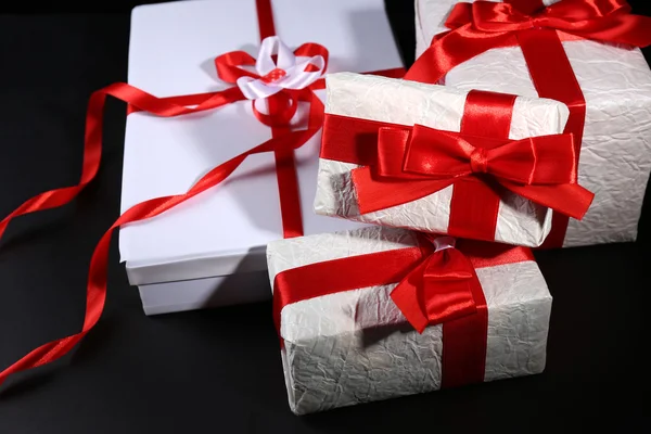 Hermosos regalos con cintas rojas, sobre fondo oscuro — Foto de Stock