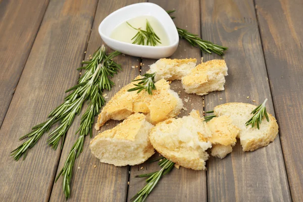 Fresh bread with olive oil and rosemary on wooden table — Stock Photo, Image