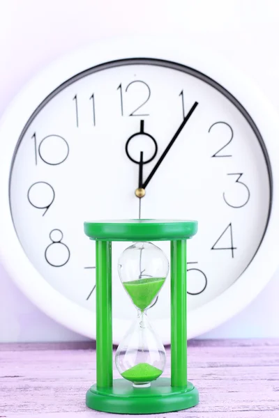 Hourglass and big clock on light background — Stock Photo, Image