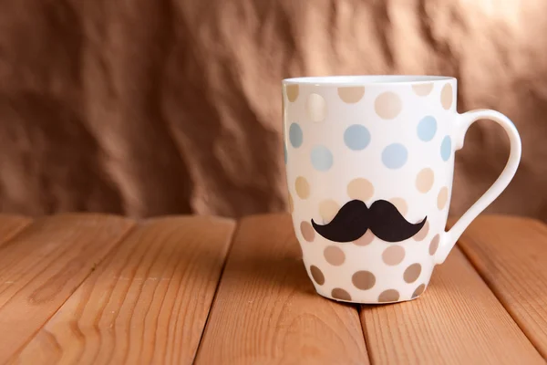 Tasse mit Schnurrbart auf Tisch auf braunem Hintergrund — Stockfoto