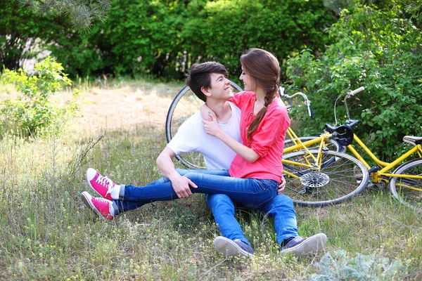 Jovem casal sentado no parque com bicicletas — Fotografia de Stock