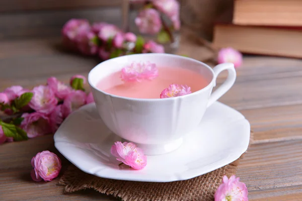 Beautiful fruit blossom with cup of tea on table on grey background — Stock Photo, Image