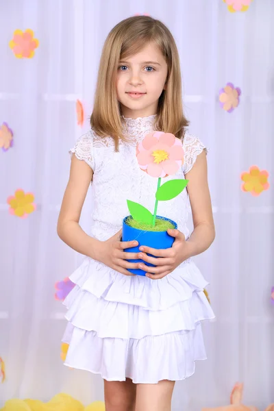 Mooi klein meisje bedrijf bloem in pot op decoratieve achtergrond — Stockfoto