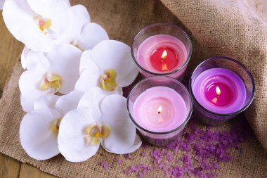 güzel renkli mumlar, deniz tuzu ve ahşap zemin üzerinde orkide çiçekleri ile kompozisyon