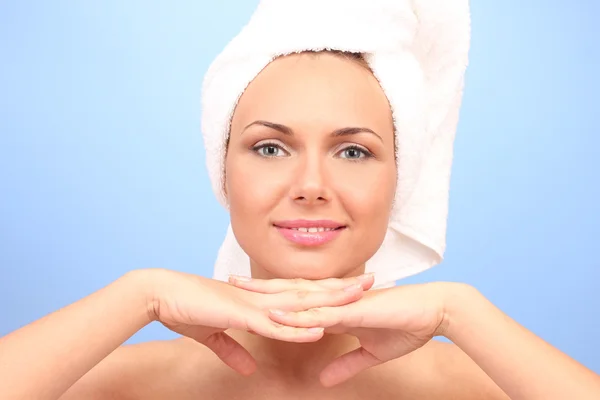 Beautiful young woman after shower with a towel on her head on blue background close-up — Stok fotoğraf