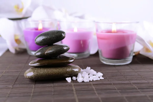 Composición con hermosas velas de colores, sal marina y flores de orquídea, sobre fondo de estera de bambú — Foto de Stock