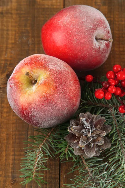 Červená jablka s jedle větev a bobule na dřevěné pozadí — Stock fotografie