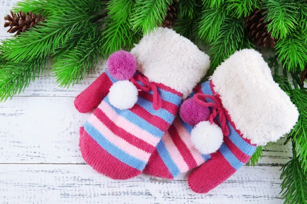 Striped mittens with fir branches on wooden background — Stock Photo, Image