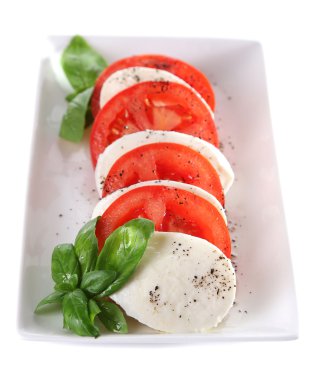 mozarella peyniri, domates ve fesleğen tabakta üzerine beyaz izole Caprese salatası