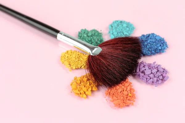 Rainbow crushed eyeshadow and professional make-up brush on pink  background — Stock Photo, Image