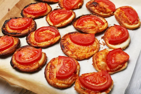 Small pizzas on baking paper close up — Stock Photo, Image