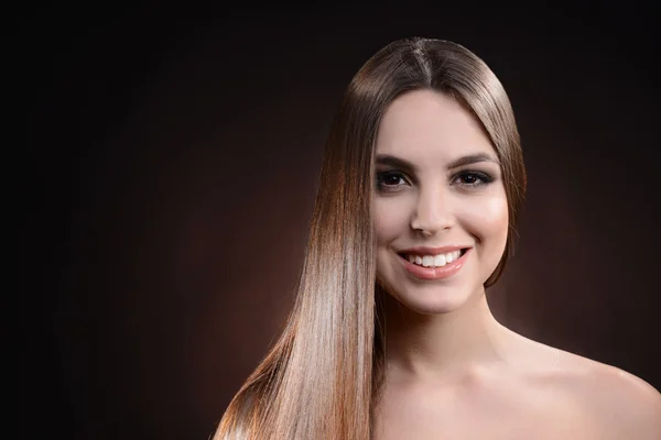 Hermosa joven con el pelo largo sobre fondo marrón oscuro — Foto de Stock