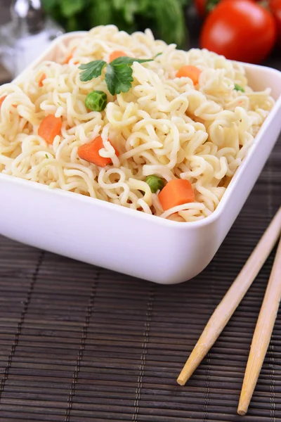 Tasty instant noodles with vegetables in bowl on table close-up — Stock Photo, Image