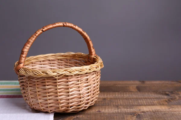 Panier en osier vide sur table en bois, sur fond sombre — Photo