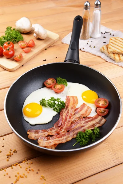 Huevos revueltos y tocino en la sartén en la mesa de cerca — Foto de Stock