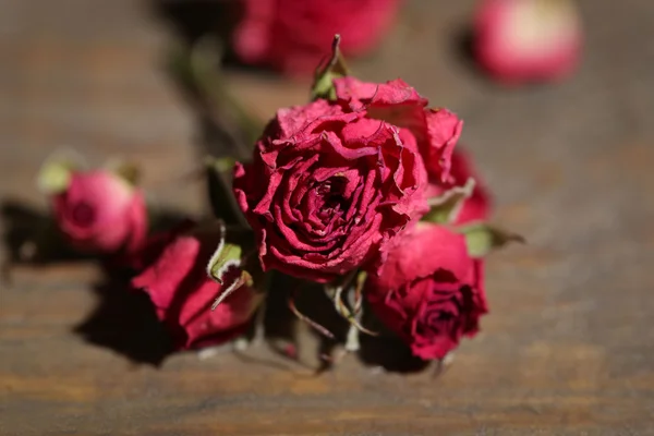 Beautiful pink dried roses on old wooden background — Stock Photo, Image