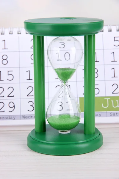 Hourglass and calendar on bright background — Stock Photo, Image