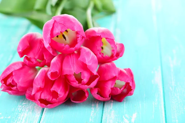 Schöne Tulpen auf farbigem Holzhintergrund — Stockfoto
