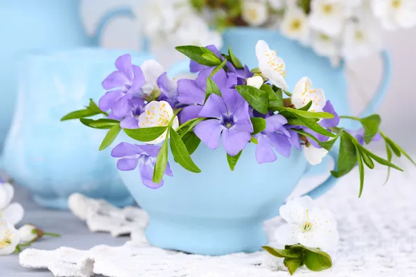 Vackra vårblommor i koppar på träbord — Stockfoto