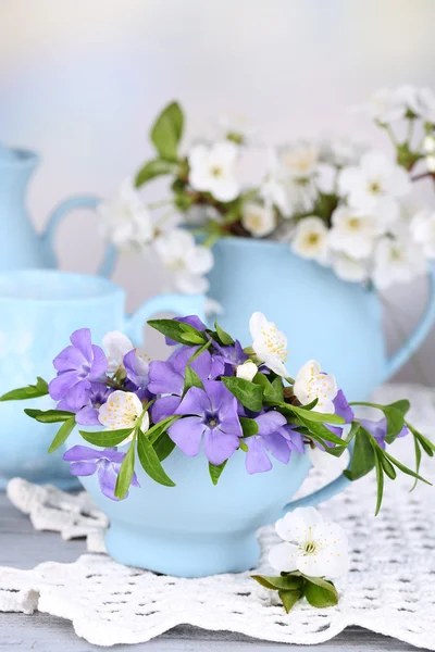 Schöne Frühlingsblumen in Tassen auf Holztisch — Stockfoto