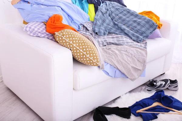 Chaotický barevné mužské oblečení na gauči na světlé pozadí — Stock fotografie