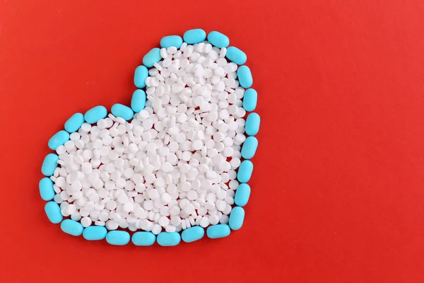 Herz aus Pillen auf rotem Hintergrund — Stockfoto