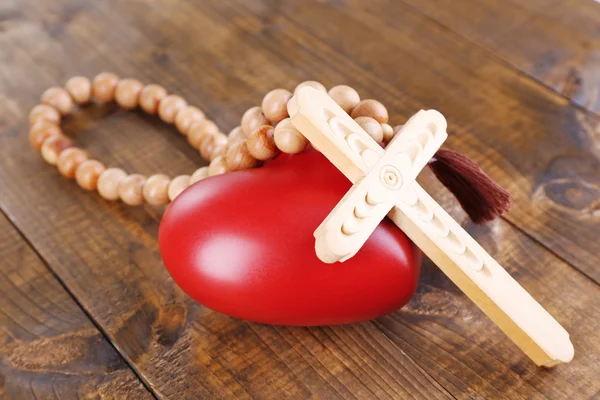 Heart with rosary beads on wooden background — Stock Photo, Image