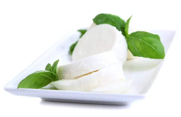 Sabroso queso mozzarella con albahaca en plato aislado en blanco —  Fotos de Stock