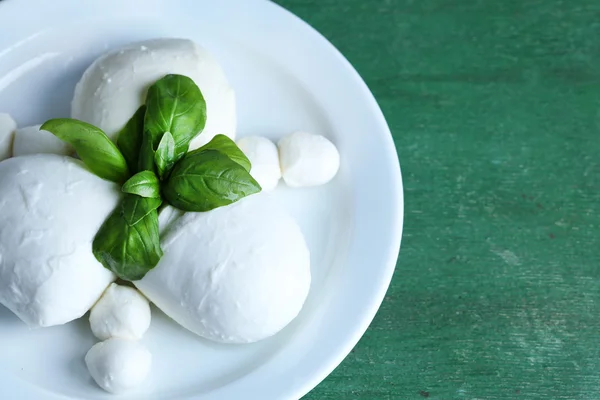 Sabroso queso mozzarella con albahaca en plato sobre fondo de madera —  Fotos de Stock