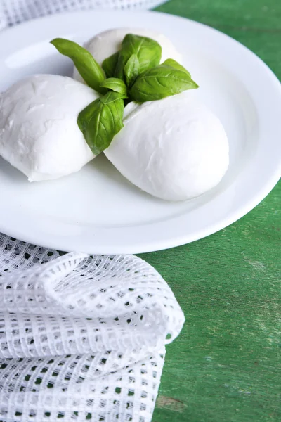 Tasty mozzarella cheese with basil on plate  on wooden background — Stock Photo, Image