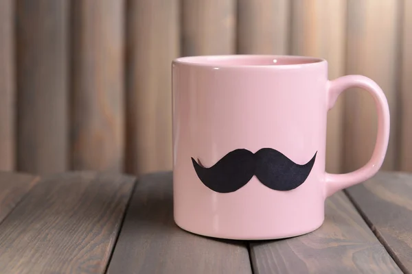 Cup with mustache on table on wooden background — Stock Photo, Image