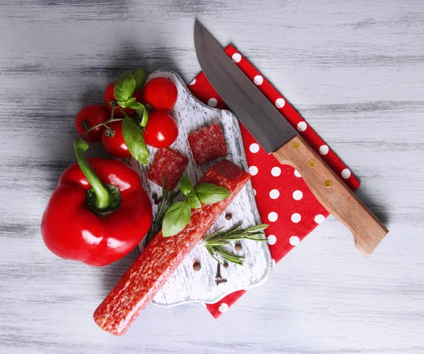 Savoureux salami saucisse, légumes, couteau et épices sur fond de bois — Photo