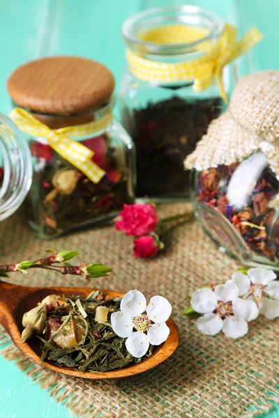 Surtido de hierbas y té en frascos de vidrio sobre fondo de madera — Foto de Stock