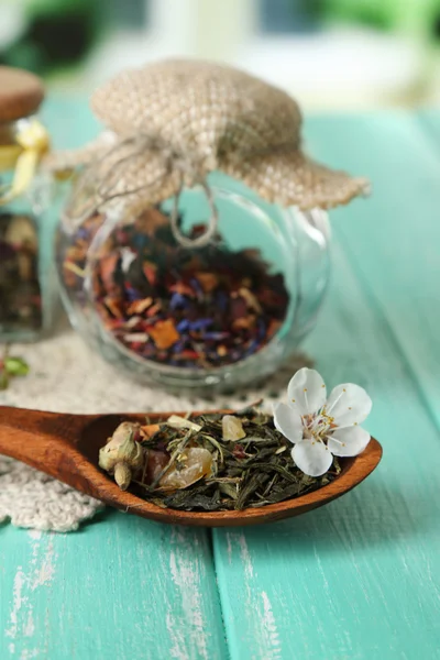 Assortiment van kruiden en thee in glazen potten op houten tafel, op lichte achtergrond — Stockfoto