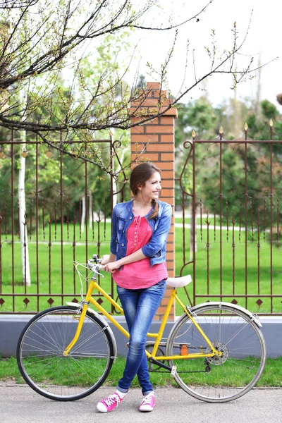 Beautiful young woman with bicycle outdoors — Stock Photo, Image