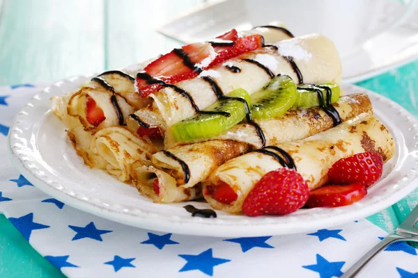 Leckere Pfannkuchen mit Erdbeeren und Schokolade auf dem Teller auf dem Tisch — Stockfoto