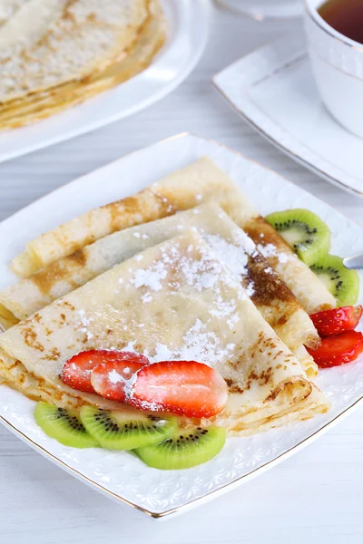 Deliciosos panqueques con fresas y chocolate en plato en la mesa —  Fotos de Stock