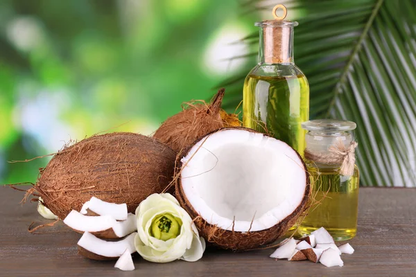 Cocos y aceite de coco sobre mesa de madera, sobre fondo natural —  Fotos de Stock