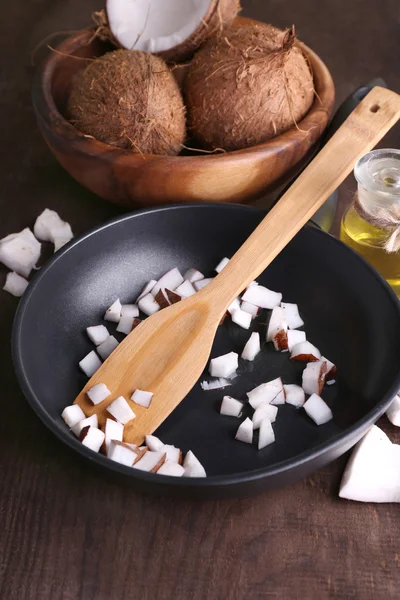 Coconuts on pan and coconut oil on wooden table — Stock Photo, Image