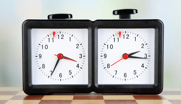 Chess clock and board on light background