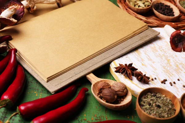 Different spices and cook book on wooden table, close up — Stock Photo, Image