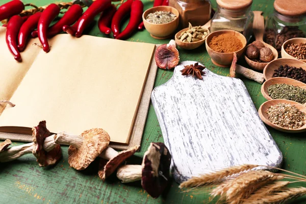 Différentes épices et livre de cuisine sur table en bois, gros plan — Photo