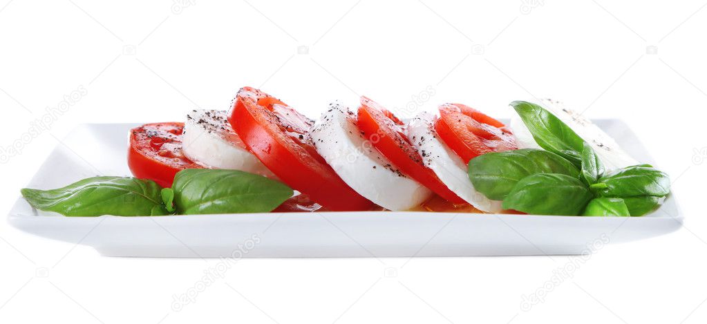 Caprese salad with mozarella cheese, tomatoes and basil on plate, isolated on white