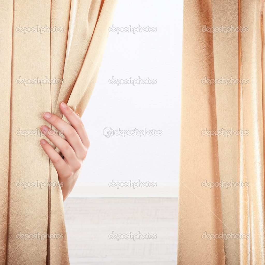 Hand opening curtain on wall background