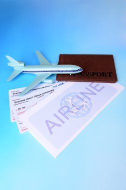 Açık mavi arka planda pasaportlu uçak biletleri.
