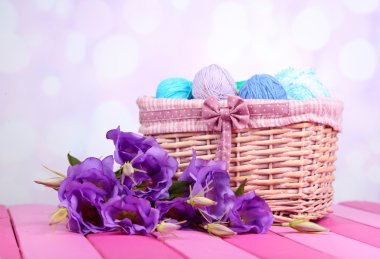 Mor yapay eustoma ve üzerinde açık renkli sepet içinde iplik yün topları